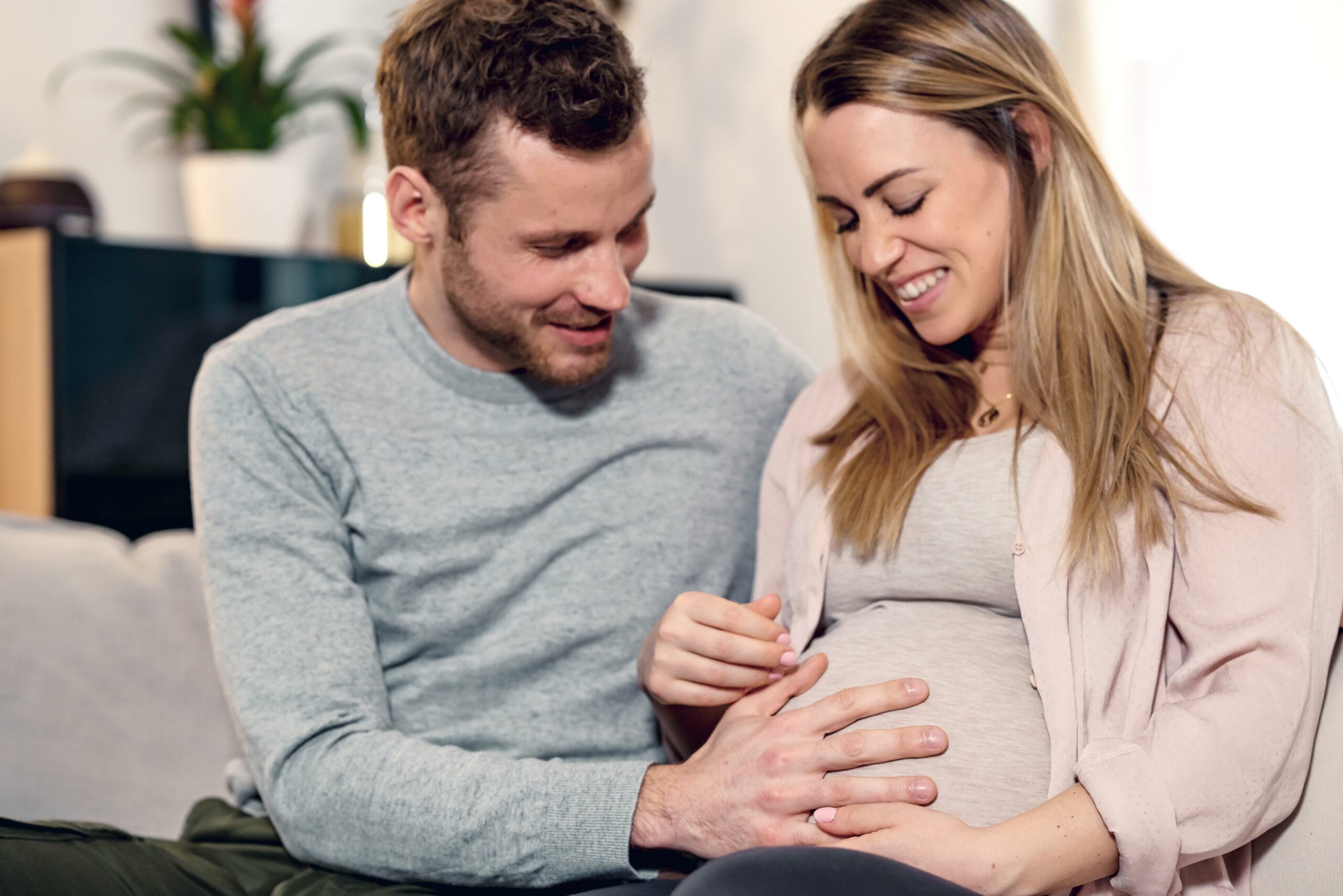 Young pregnant couple sitting on a couch